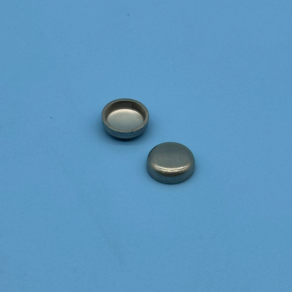 Two stainless steel cup-shaped sealing caps included with the Audi secondary air cleaning kit.