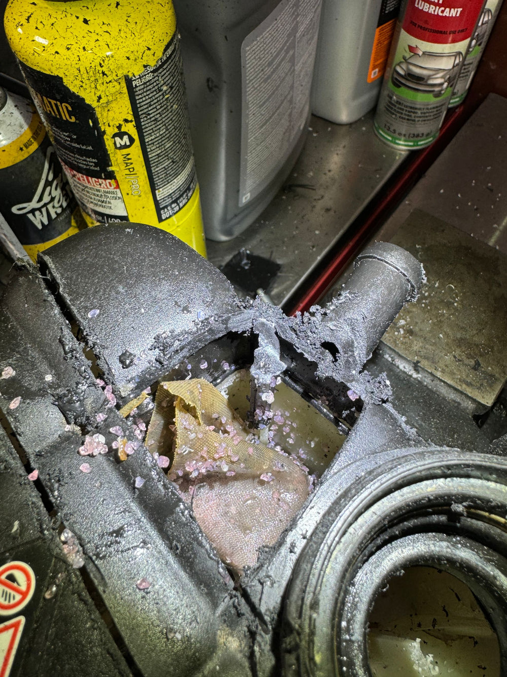 Failed Mercedes coolant housing clogged with a ruptured filter bag and pink-white crystalline debris.
