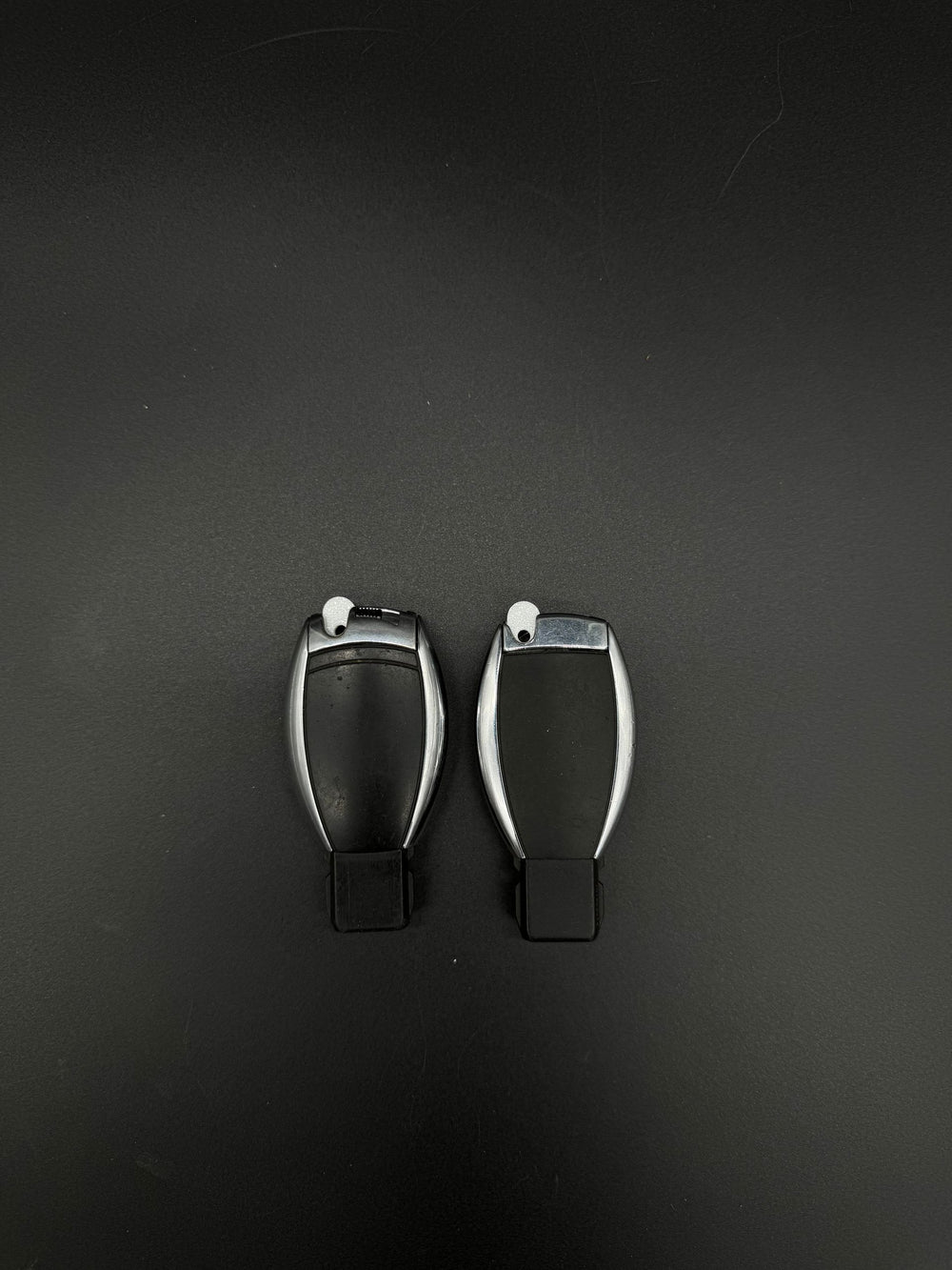 Back of two Mercedes-Benz smart keyfobs showing white GEN-2 emergency blade blanks (PN MBZ002) seated.