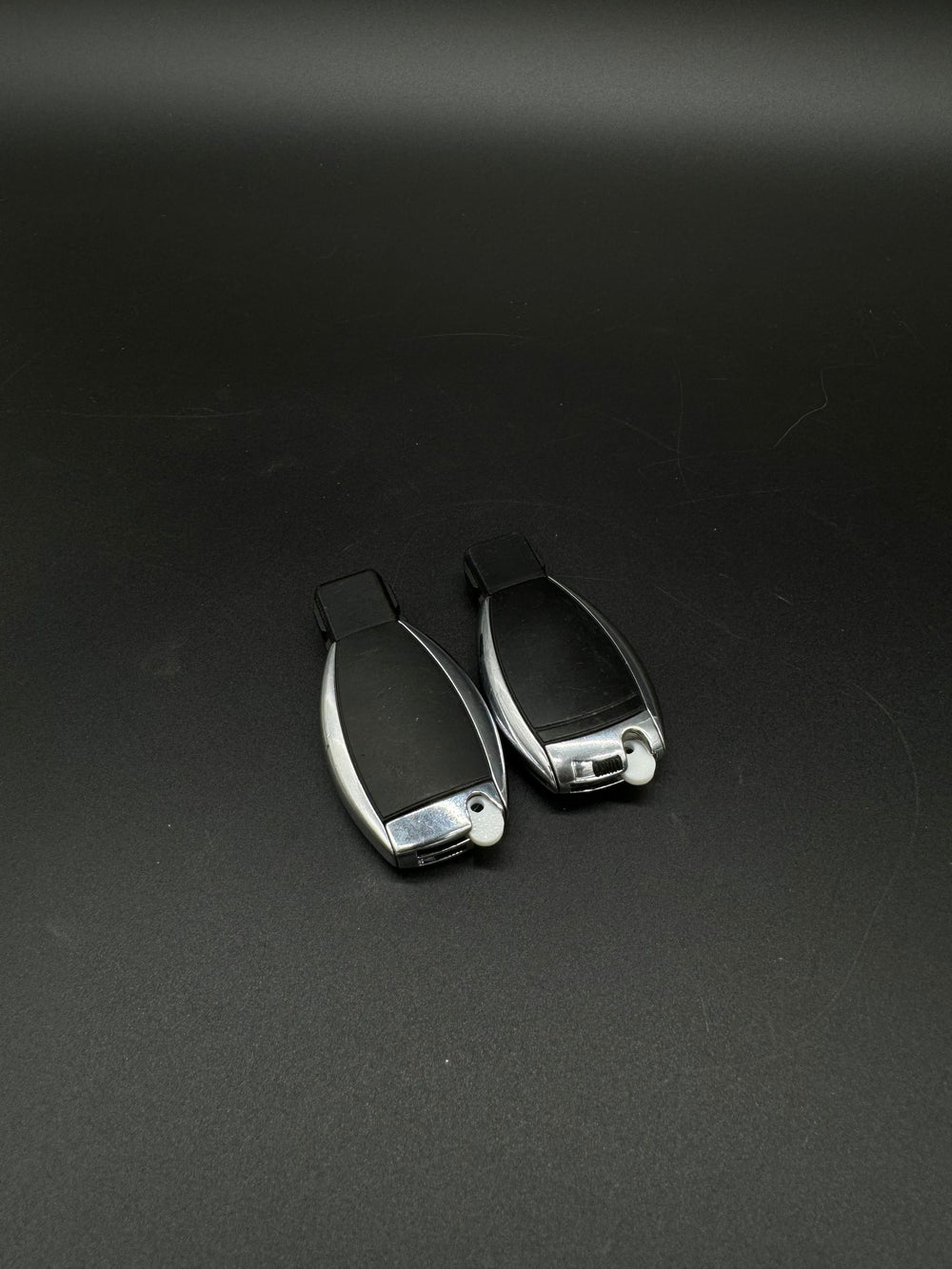 Two chrome and black Mercedes-Benz smart keyfobs with white GEN-2 blade blanks (PN MBZ002) installed.