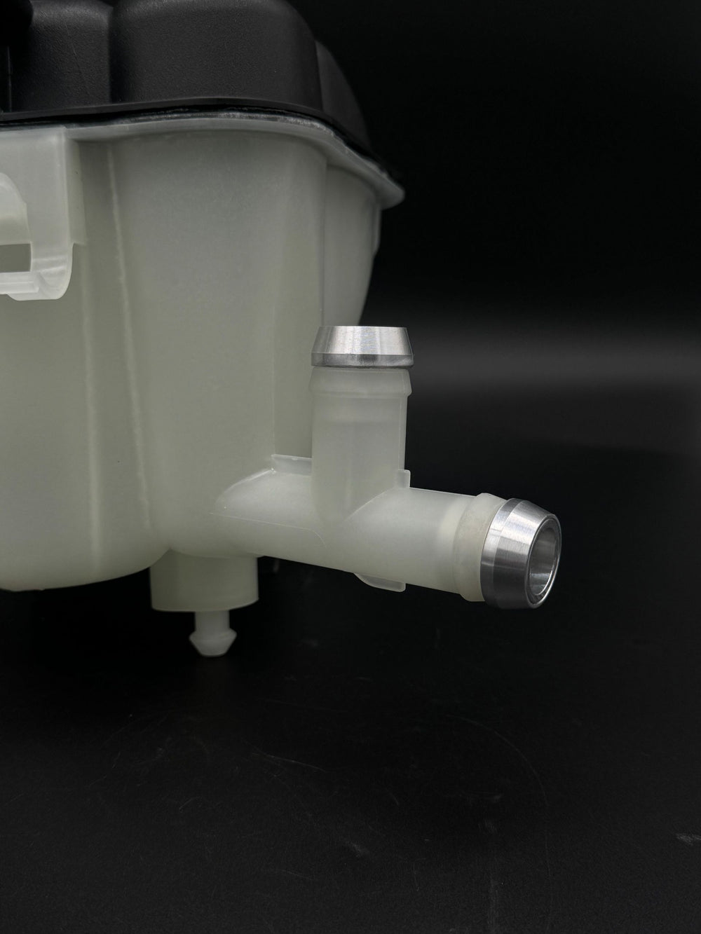 Close-up of bare aluminum CNC barb fittings pressed into the Mercedes ML/GL coolant tank hose ports.