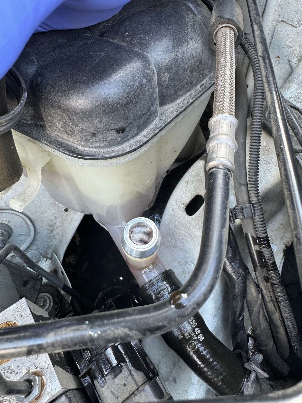Installed shot of bare aluminum CNC barb fitting on Mercedes ML/GL coolant expansion tank in the engine bay.