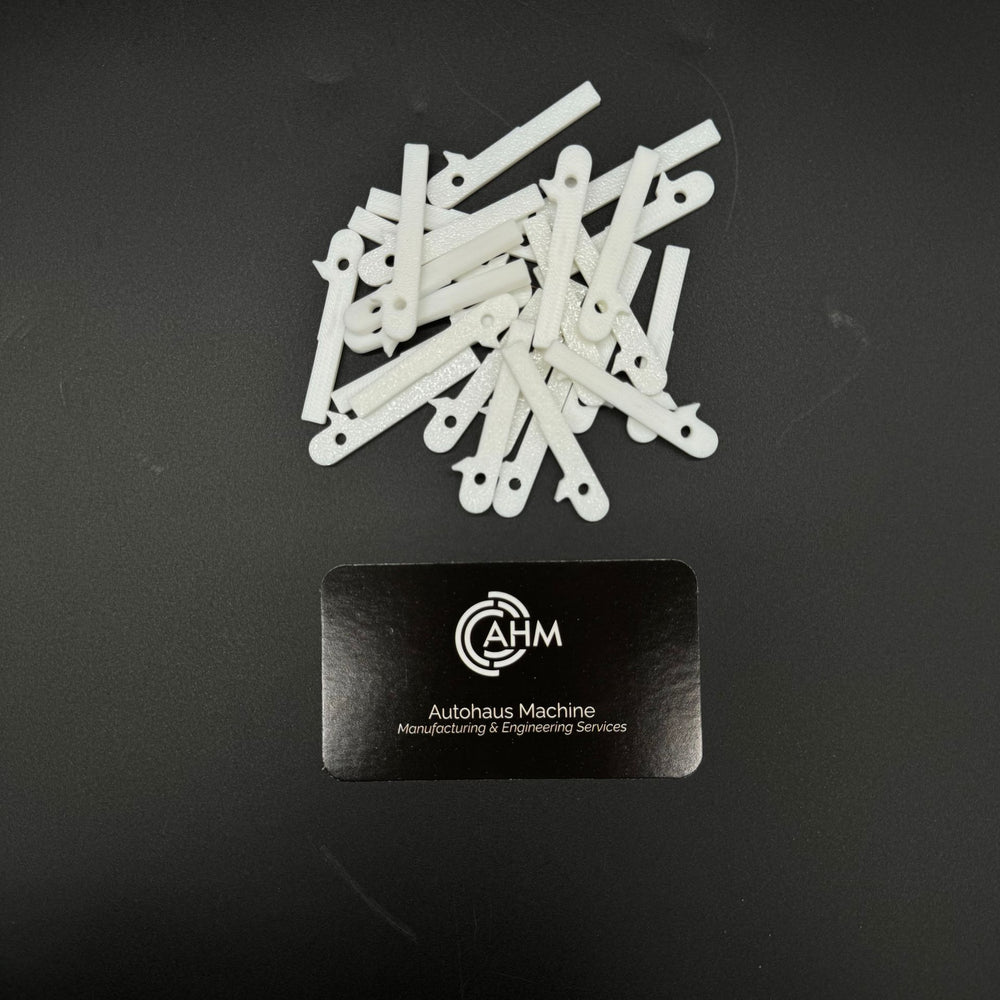 Loose pile of white GEN-2 Mercedes-Benz key blade blanks (PN MBZ002) beside an Autohaus Machine card.