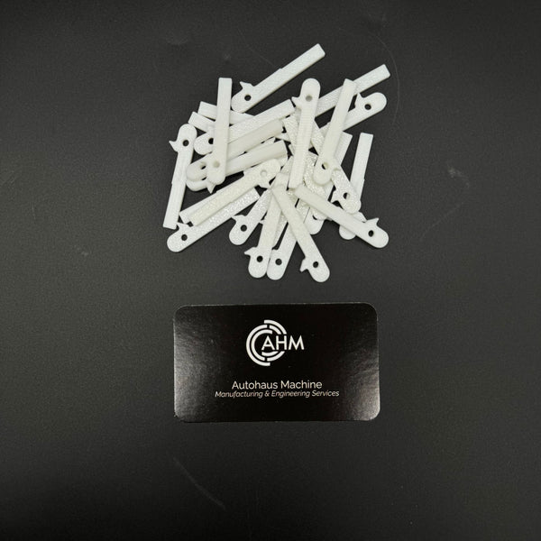 Loose pile of white GEN-2 Mercedes-Benz key blade blanks (PN MBZ002) beside an Autohaus Machine card.