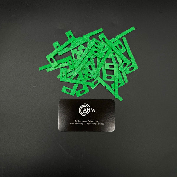 Loose pile of green GEN-3 Mercedes-Benz key blade blanks (PN MBZ003) beside an Autohaus Machine card.