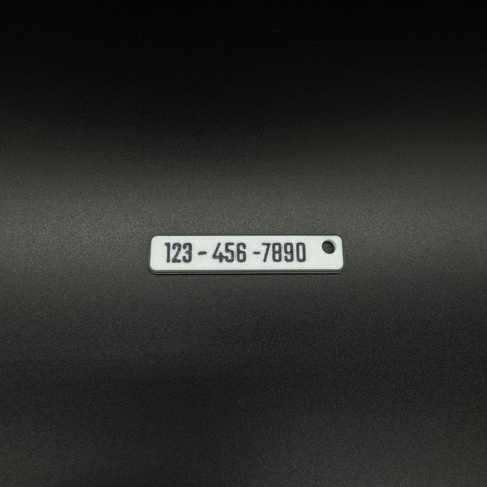 Euro-plate dealership keychain showing custom service phone number 123-456-7890 in black.