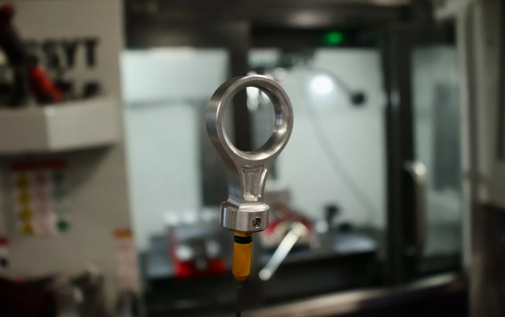 Aluminum Mazda Miata dipstick handle installed on a dipstick, shown inside a CNC machine.