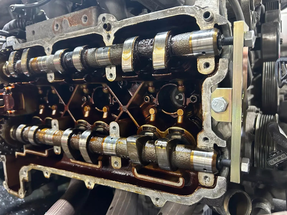 Cam locking tool installed across the camshafts on an open Porsche 996 3.4L engine head during a valve cover job.